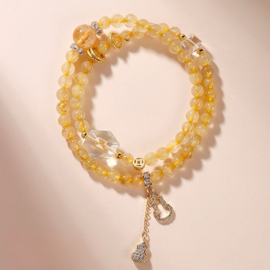 Golden rutilated quartz bead bracelet with a gourd charm, showing golden rutile needles inside clear quartz