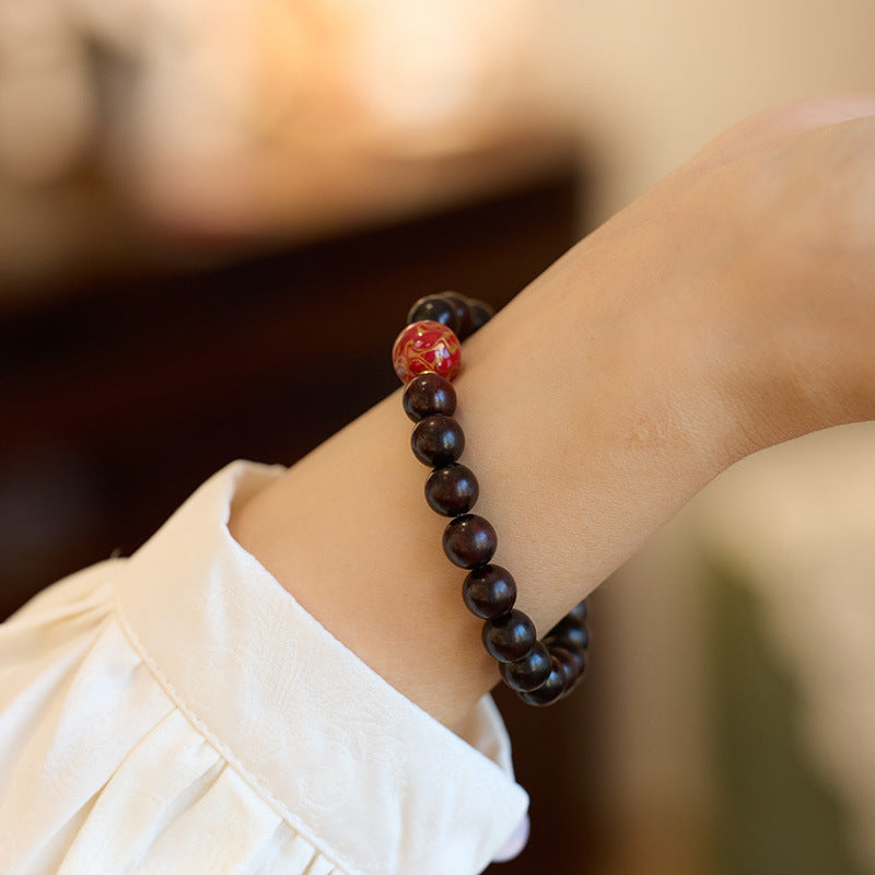 Small leaf red sandalwood bracelet with colorful lacquer beads on a wrist